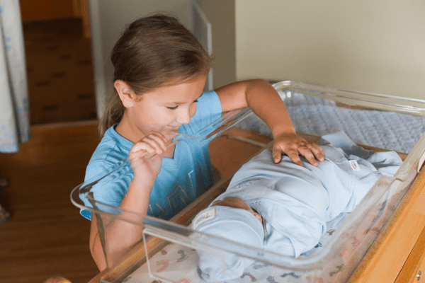 big sister touching baby for the first time